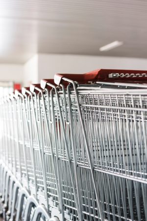 Row of metal supermarket trolleys lined up inside a shop entrance.